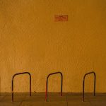 STOPM_2020_418e: Photograph of a mustard yellow wall, with a bike rack in the foreground, taken by Jake Bowden. Thumbnail